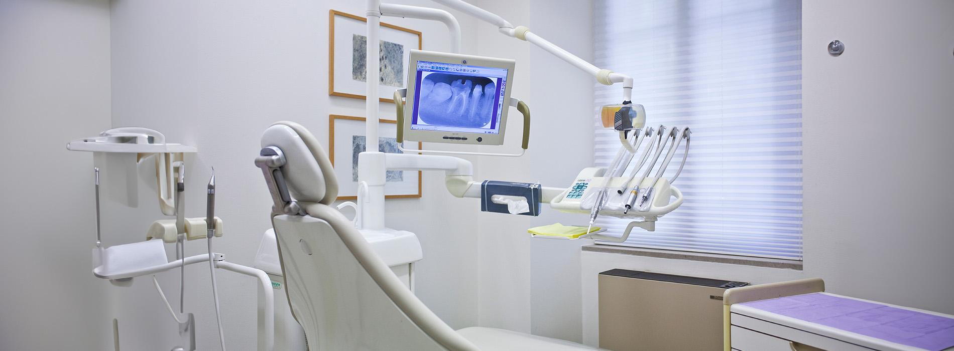 The image shows a modern dental clinic interior with various pieces of equipment, including a dental chair and an X-ray machine.