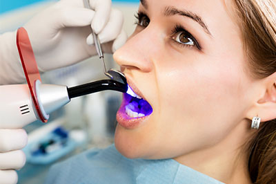 A dental hygienist is using a device to clean a patient's teeth.