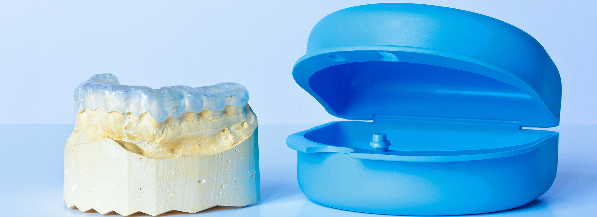 An image featuring a blue dental model and a yellow toothpaste sample, set against a white background.